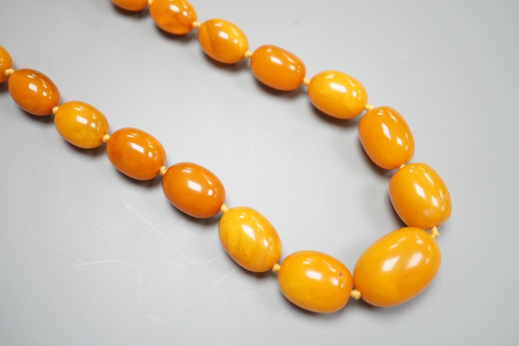 A single strand graduated oval amber bead necklace, 65cm and a similar bracelet, 18cm, gross weight 82 grams.